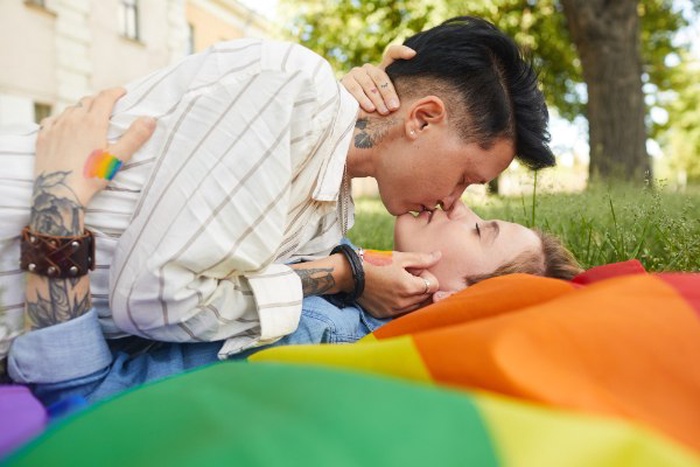 queers lying on green grass and kissing each other