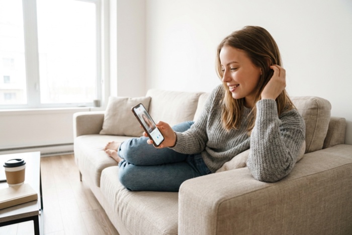 Young woman using a dating app on her phone at home